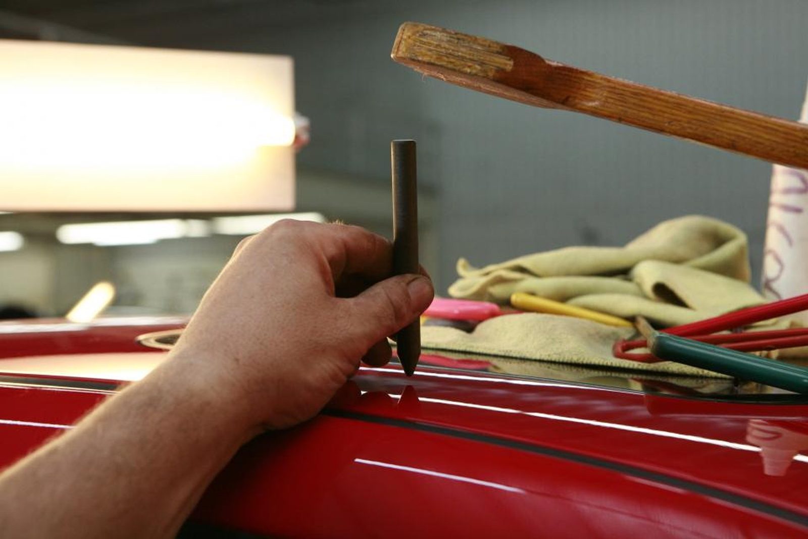Technician working by hand along the roof edge of a red car